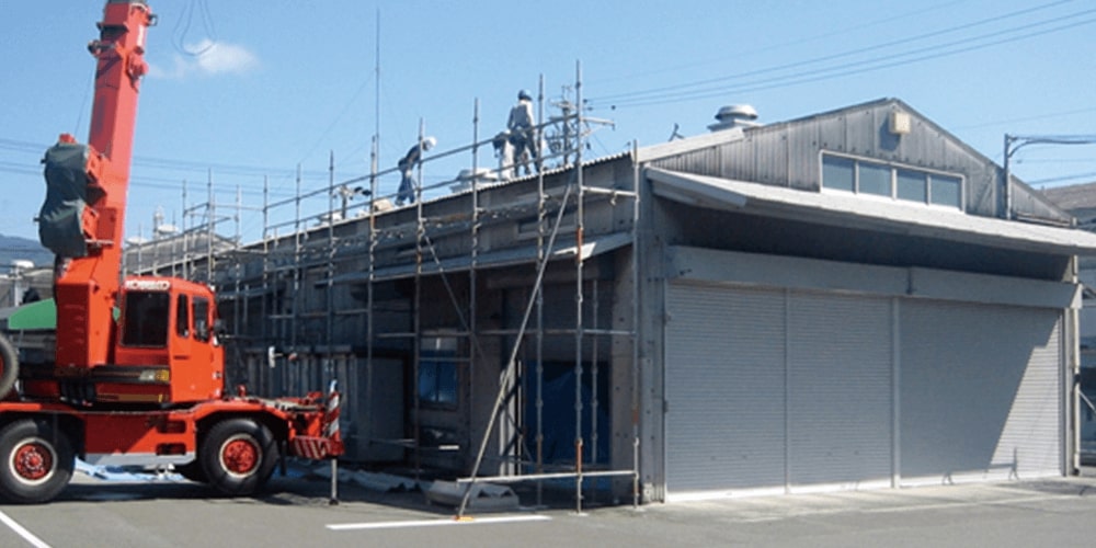 重機を使って屋根の上で仕事をする作業員