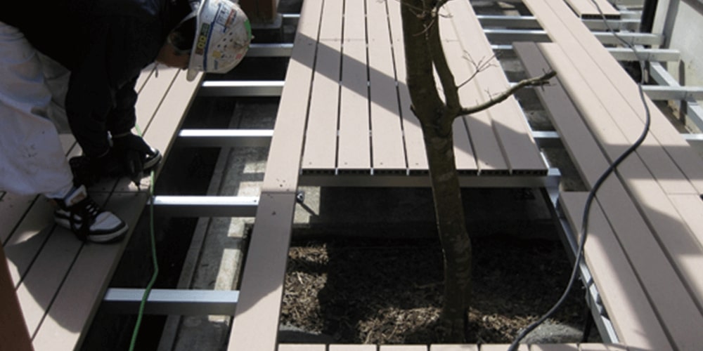 ウッドデッキの中の鉄に木をくっつけている社業員